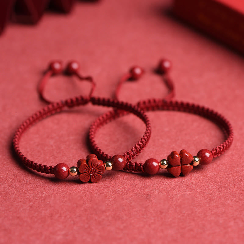 Red cord bracelet with cinnabar five-petal flower charm, gold spacer beads and polished red stone beads displayed with raw cinnabar fragments on red background