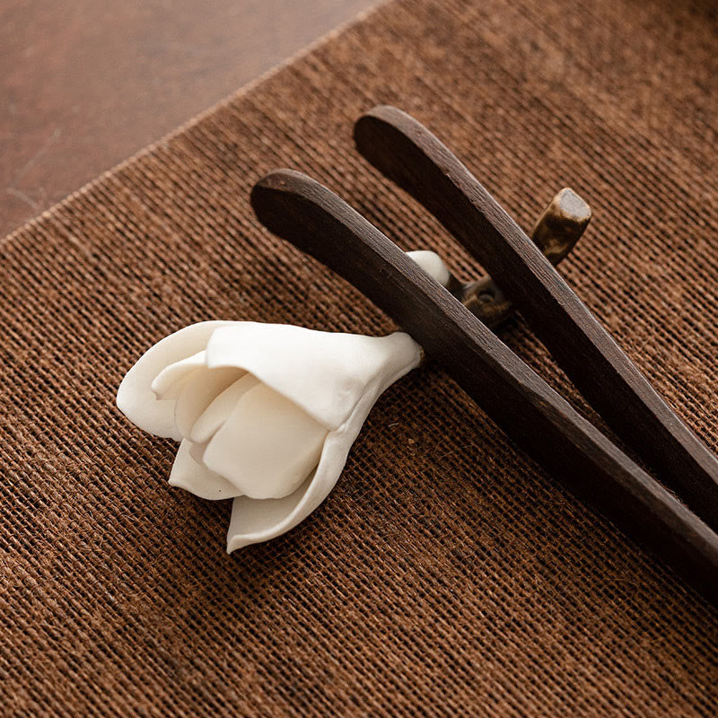 Gardenia Ceramic Incense Burner – Flower gripped by dark wooden tongs on coarse woven mat, artisan craft