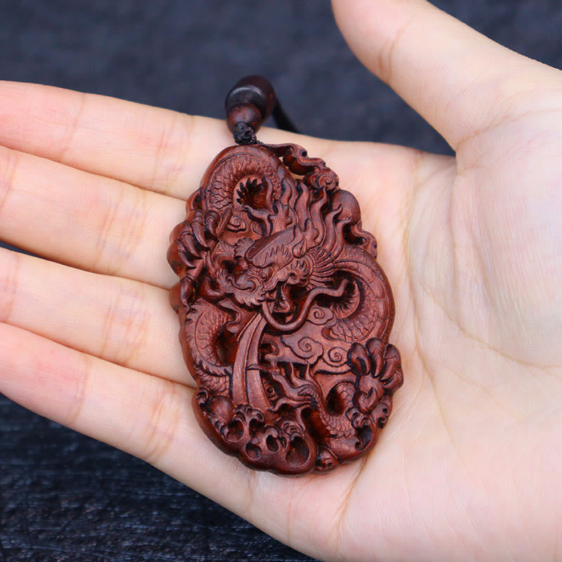 Lightning Jujube Wood Dragon Pendant - Palm-held on dark textured fabric, carving depth, Gift