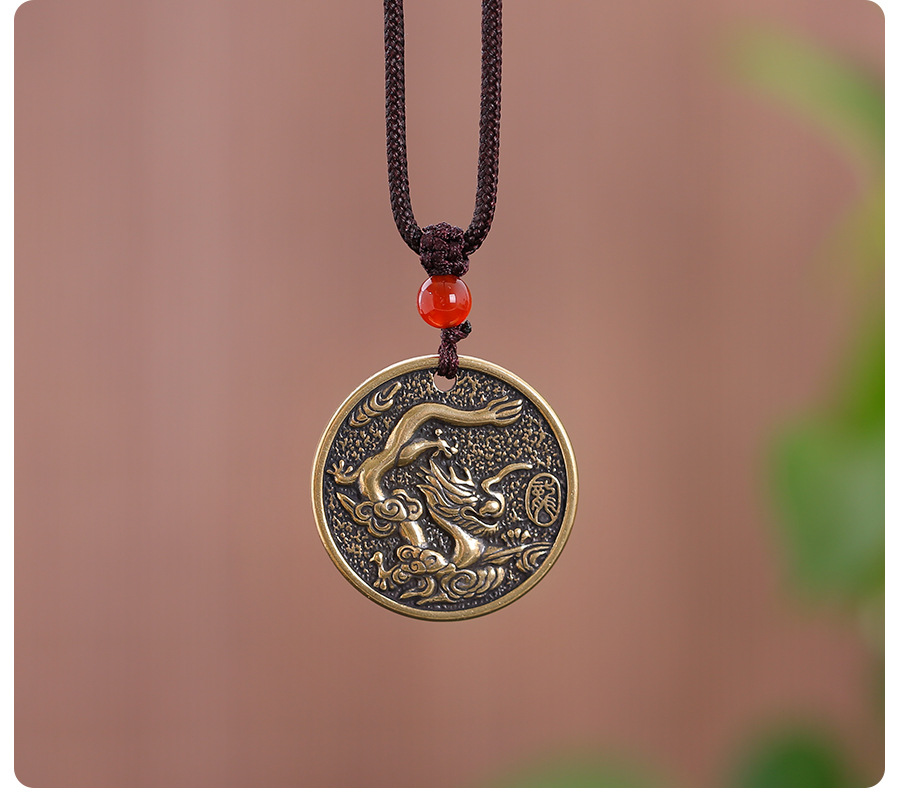 Zodiac Bagua Pendant – brass dragon pendant hanging on cord with soft green bokeh, lifestyle shot