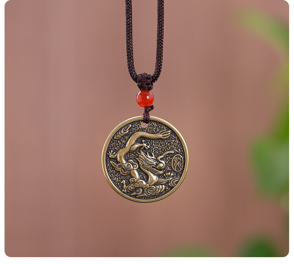 Zodiac Bagua Pendant – brass dragon pendant hanging on cord with soft green bokeh, lifestyle shot