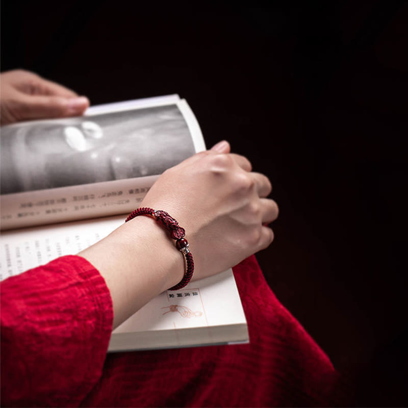 Handcrafted PiXiu Cinnabar Wealth Luck Braided Bracelet – hands turning book page wearing bracelet, lifestyle shot