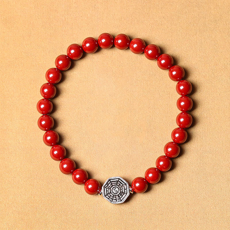 925 Sterling Silver Yin Yang Bagua Cinnabar Bracelet – Red beaded bracelet with silver Bagua charm, flat lay on tan backgroun
