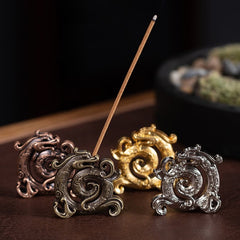 Mini Dragon Incense Burner – Four metallic dragon holders in bronze, brass, gold and silver finishes on dark wood, Meditation
