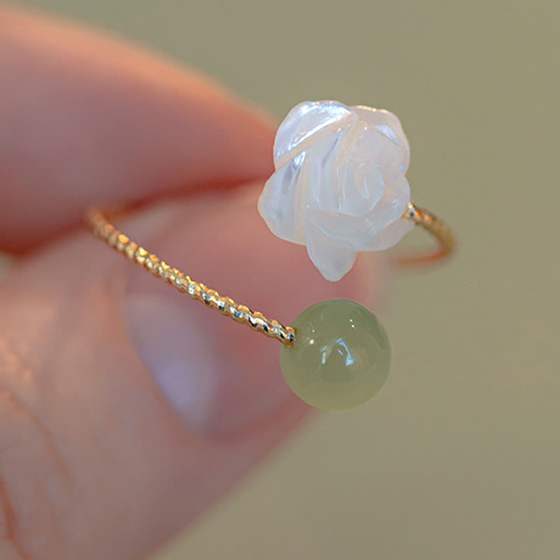14K Gold Tridacna Jade Rose Ring – Gold twisted wire band with white shell rose and green jade bead, macro close-up on beige bokeh background