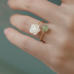 14K Gold Tridacna Jade Rose Ring – Two stacked rings with white mother-of-pearl rose and green jade bead on gold bands, teal green background, macro view