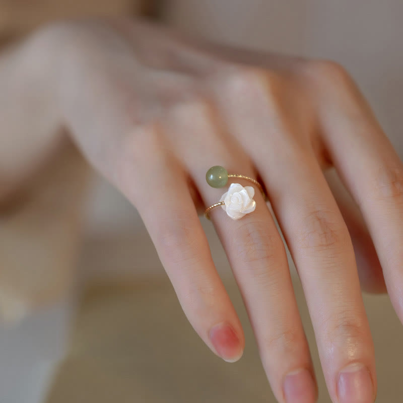 14K Gold Tridacna Jade Rose Ring – Gold open cuff ring with white lotus carved stone and sage green jade bead, warm beige background side view