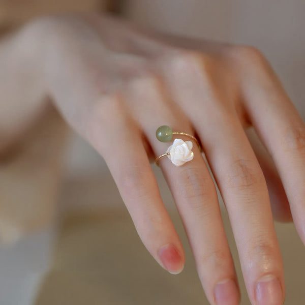 14K Gold Tridacna Jade Rose Ring – Gold open cuff ring with white lotus carved stone and sage green jade bead, warm beige background side view