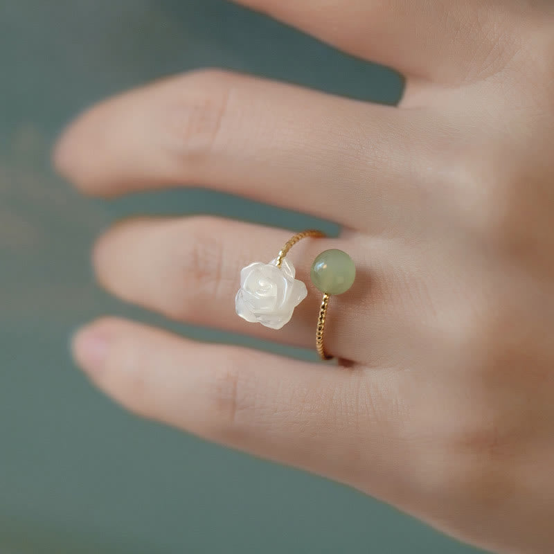 14K Gold Tridacna Jade Rose Ring – Gold ring with white jade rose and green jade bead on finger, soft teal background, close-up side angle
