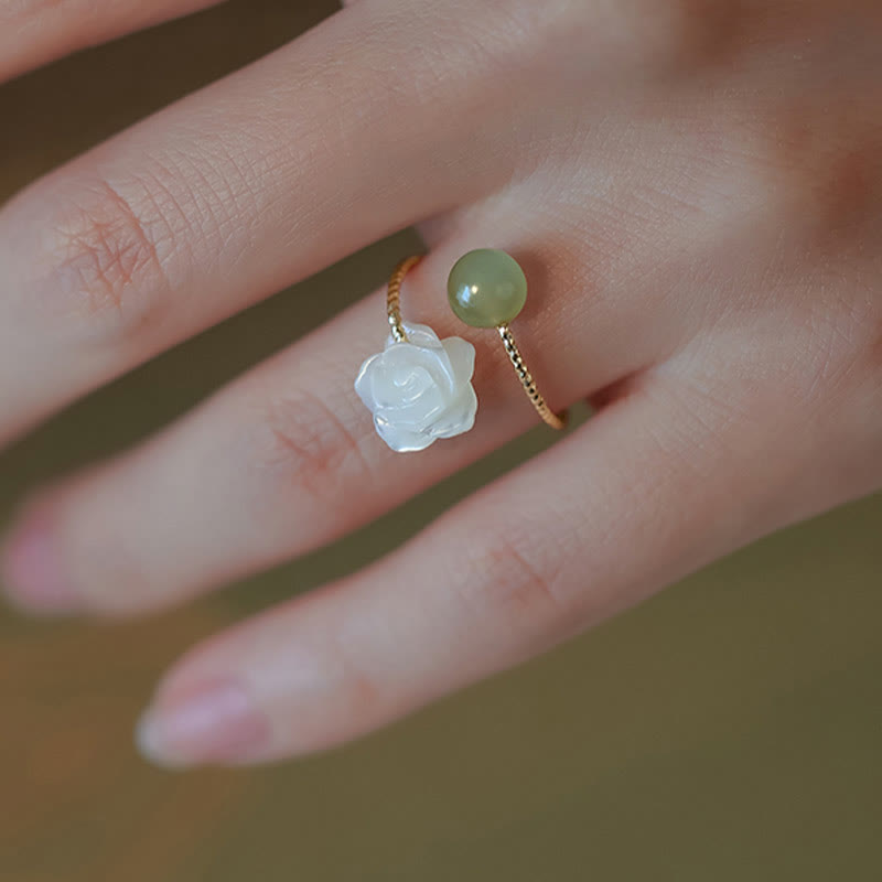 14K Gold Tridacna Jade Rose Ring – Gold twisted wire ring with mother-of-pearl rose and green jade bead, macro close-up on blurred skin background