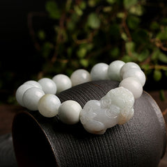 Jade PiXiu Bracelet – On dark pottery with green foliage background, natural setting, prosperity luck bracelet