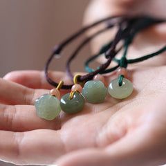 Jade Peace Buckle Lotus Necklace – Four jade pendants with lotus pod and bi-disc on colored cords in palm, jade necklace