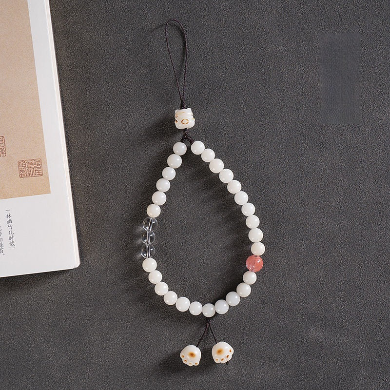 White Jade Bodhi & Jadeite Crystal Phone Charm – White bodhi beads with clear quartz and strawberry crystal accents beside traditional book
