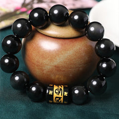 Rainbow Obsidian Bracelet – Black beads with gold mantra charm displayed on ceramic pot, spiritual jewelry