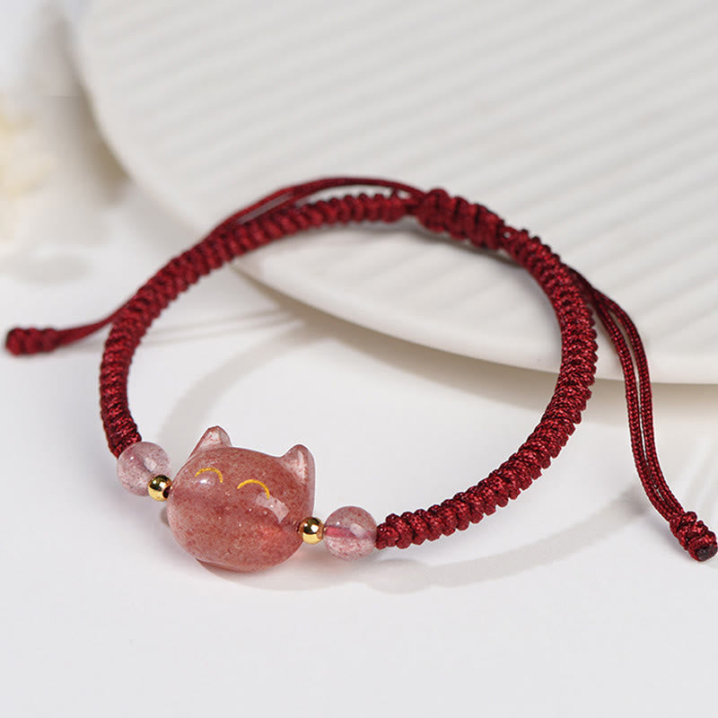 Adjustable burgundy macrame cord bracelet with carved strawberry quartz cat charm, gold accents and pink stone beads on white background