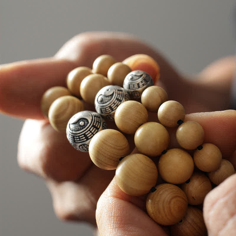 Peach Wood Cinnabar Bracelet – Three yin yang bagua metal beads held in cupped hands, luck protection