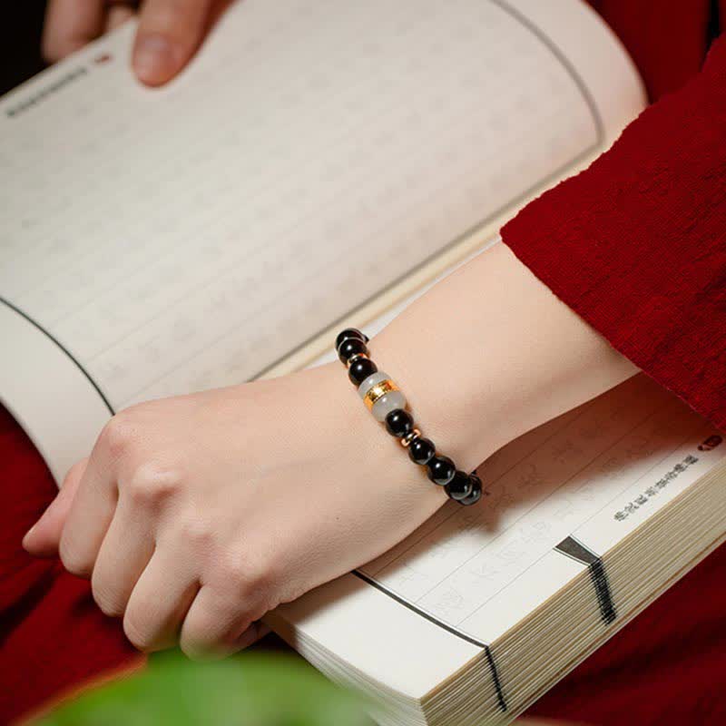 Black Obsidian Jade Bracelet – Wrist shot with traditional Chinese book and clothing, cultural styling