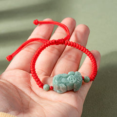 Jade PiXiu Knot Bracelet – Hand holding red cord bracelet with light green jade PiXiu charm, detail view