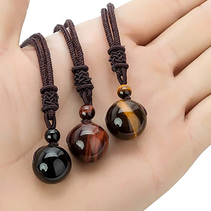 Tibetan Tiger Eye Obsidian Amethyst Protection Necklace – Three sphere pendant necklaces in black onyx, red tiger's eye, and golden tiger's eye held in hand