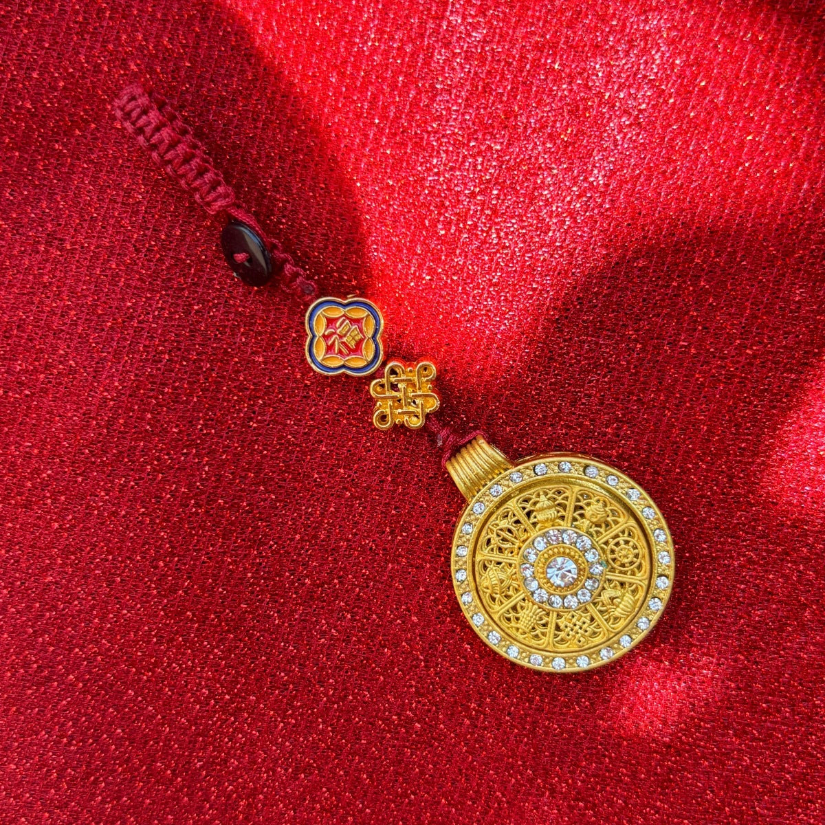 Gold enamel calabash keychain with ruyi pattern, gold cord on pink fabric