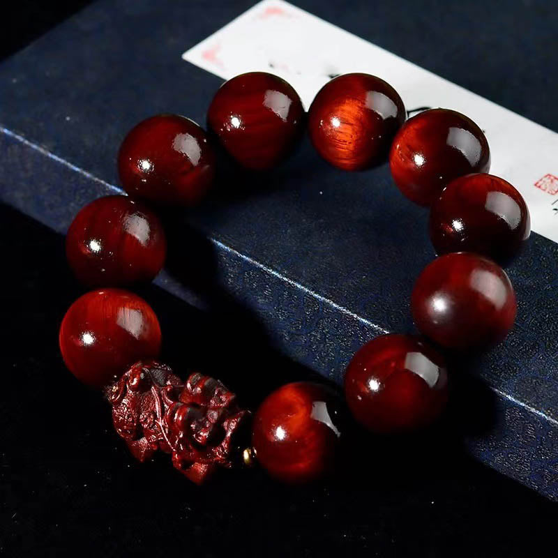 Red Sandalwood PiXiu Bracelet – Lustrous red beads on dark blue book with calligraphy paper, mindfulness