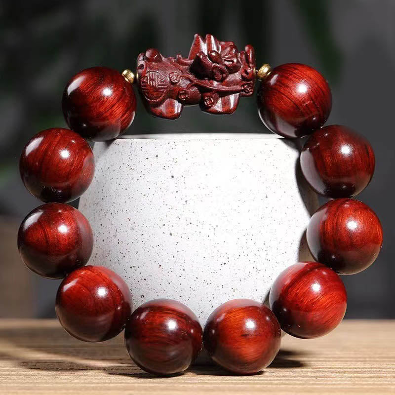 Red Sandalwood PiXiu Bracelet – Deep red polished wood beads with carved PiXiu on white ceramic cup, zen
