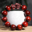 Red Sandalwood PiXiu Bracelet – Deep red polished wood beads with carved PiXiu on white ceramic cup, zen