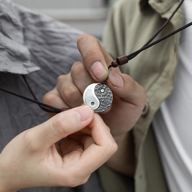 Sterling Silver Yin Yang Pendant - Two hands holding round yin-yang pendant necklace on black cord, balance harmony jewelry