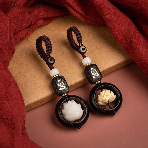 Ebony Wood Bodhi Seed Lotus Key Chain - two lotus color variants on burgundy fabric Imagen principal del producto