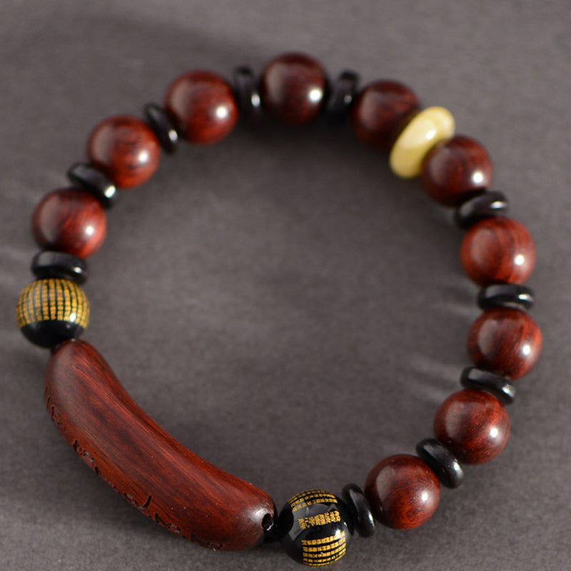 Red Sandalwood Om Bracelet – overhead on charcoal, reddish-brown wood beads with mantra barrel, mens wooden jewelry