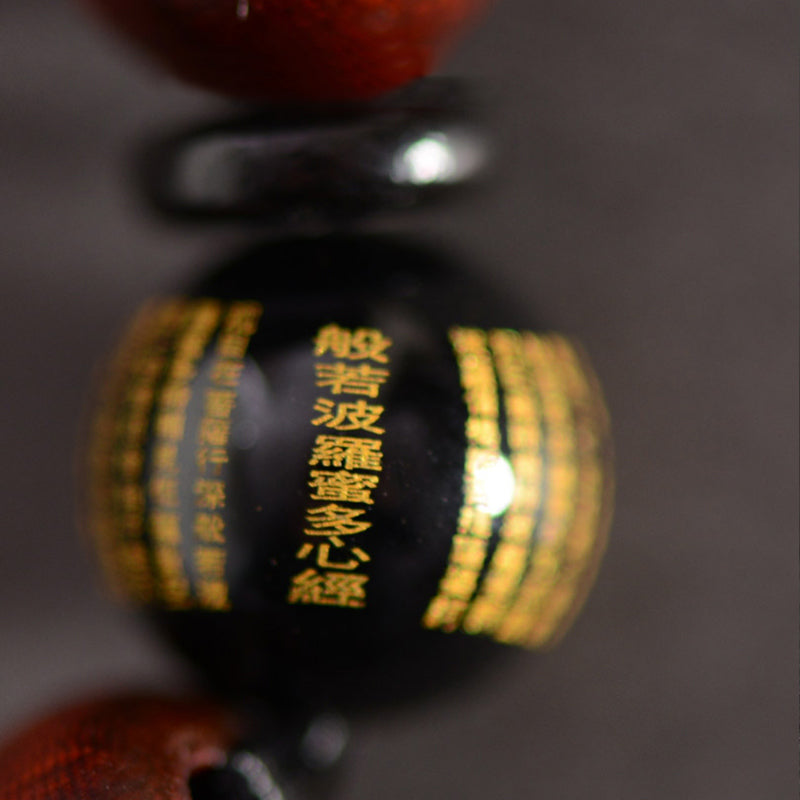 Red Sandalwood Om Bracelet – close-up of black bead with gold Heart Sutra engraving, Buddhist scripture bead detail