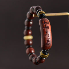 Red Sandalwood Om Bracelet – suspended view on dark background, wood beads with gold-patterned accents, mala bead bracelet