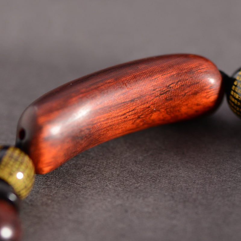 Red Sandalwood Om Bracelet – side profile of polished curved wood bead showing natural grain texture, wooden prayer beads