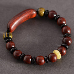 Red Sandalwood Om Bracelet – top-down on dark gray fabric, full wood bead circle with black spacers, mens sandalwood bracelet