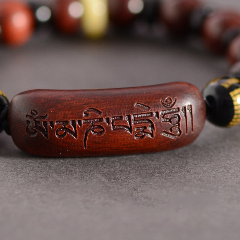 Red Sandalwood Om Bracelet – macro detail of carved Tibetan mantra on curved wood center bead, sandalwood healing bracelet
