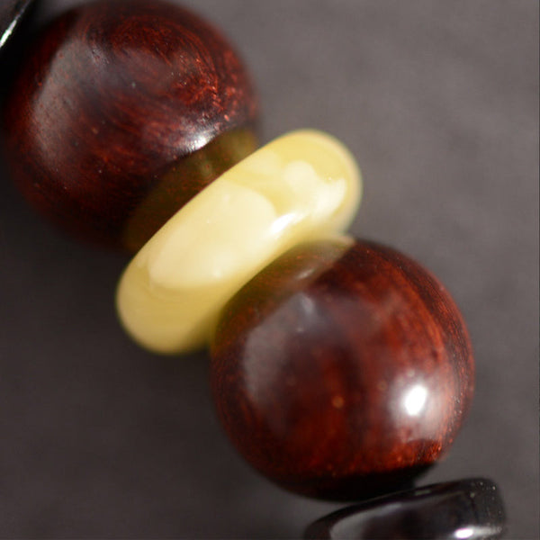 Red Sandalwood Om Bracelet – close-up of polished red wood beads with cream spacer, natural sandalwood texture detail