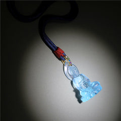 Blue Tathagata Medicine Buddha Liuli Crystal Necklace – pale aquamarine pendant with gold multi-stone bail and braided navy cord, red knot fastener, light gray surface