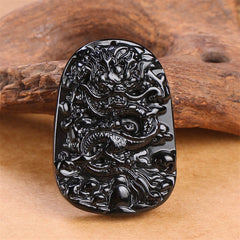Black Obsidian Dragon Carved Pendant – Frontal relief dragon carving on weathered wood, spiritual craftsmanship