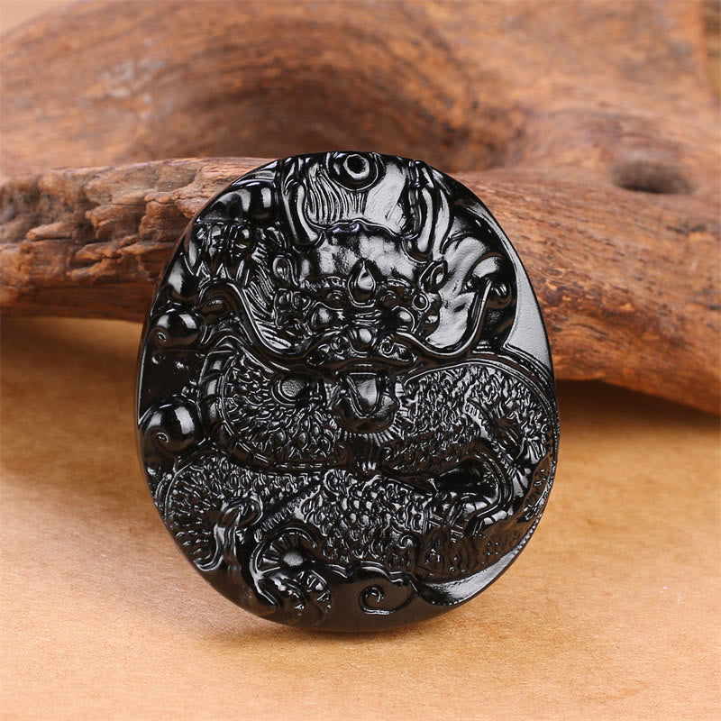 Black Obsidian Round Dragon Pendant – oval dragon relief on warm wood with earthy tones, traditional