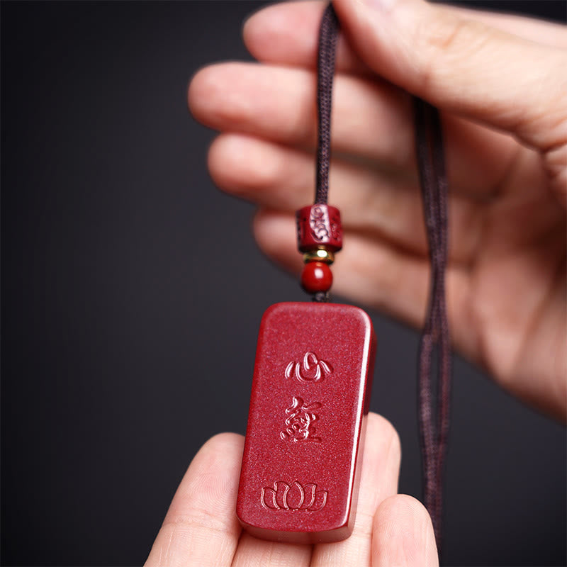 Cinnabar Heart Sutra Necklace – hand-model view showing carved lotus and sutra relief on red stone