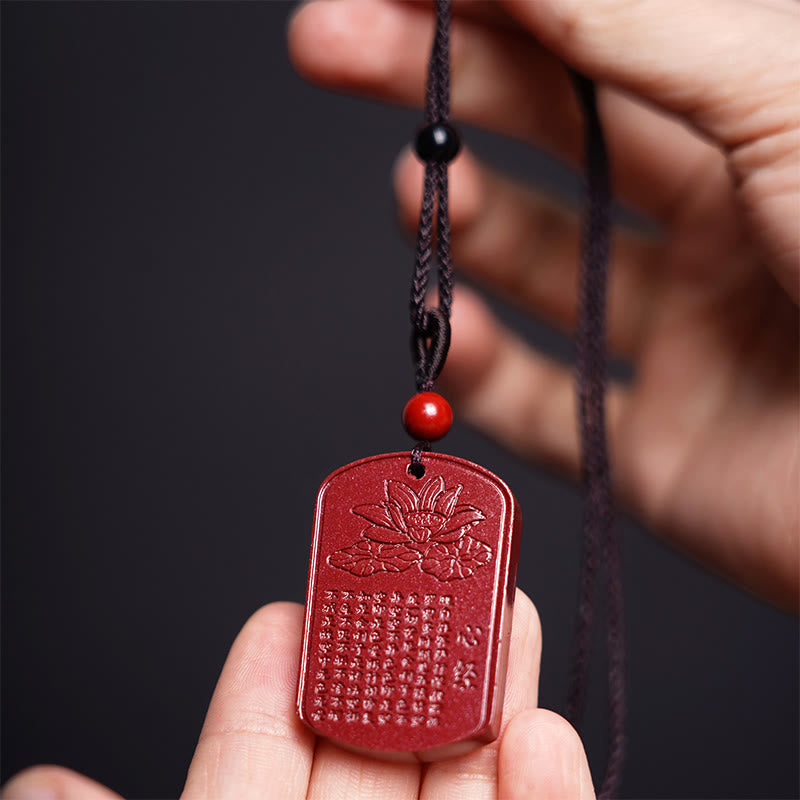 Cinnabar Heart Sutra Amulet – held in hands showing lotus relief and carved sutra text, spiritual jewelry