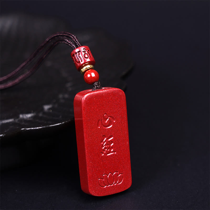 Cinnabar Heart Sutra Pendant – side angle revealing carved text and bottom lotus motif on dark surface
