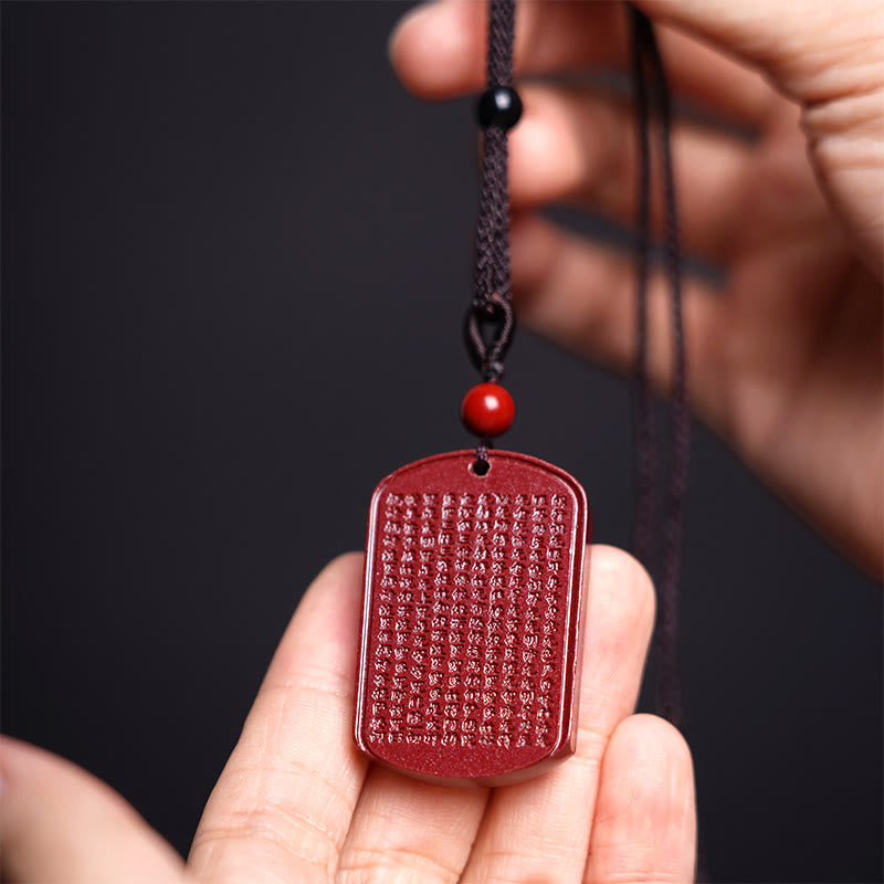 Red Cinnabar Pendant Necklace – hand-held view revealing carved text texture and cord details, Buddhist talisman