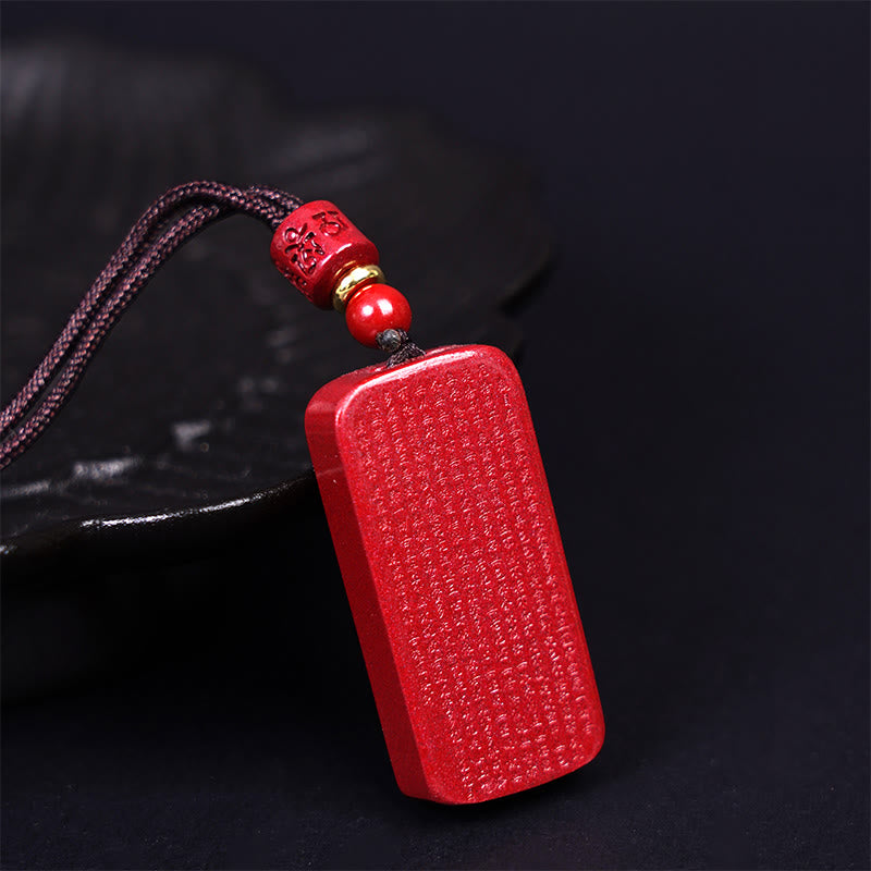 Red Cinnabar Amulet – diagonal view showing dense sutra carving and cylindrical bead detail, spiritual pendant