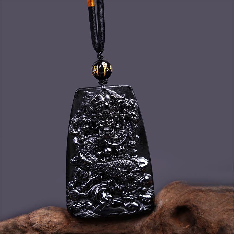 Black Obsidian Dragon Carved Pendant – Straight-on view of dragon relief carving on natural wood, bold