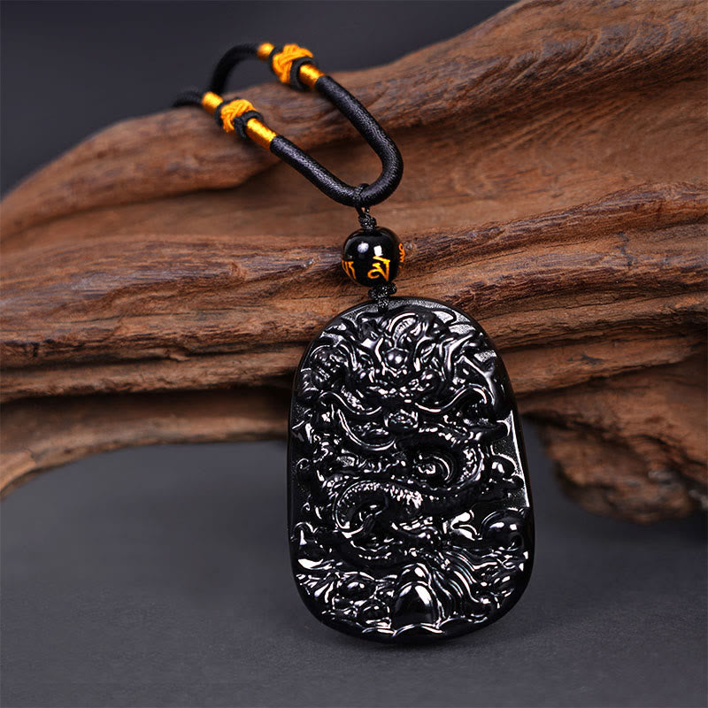 Black Obsidian Dragon Carved Pendant – Three-quarter view of coiled dragon relief with cloud motifs, powerful
