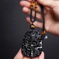 Black Obsidian Dragon Carved Pendant – Hand-held view showing carved dragon detail and adjustable cord, grounding
