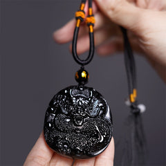 Black Obsidian Round Dragon Pendant – dragon disc held in hands with cord and amber beads, protective