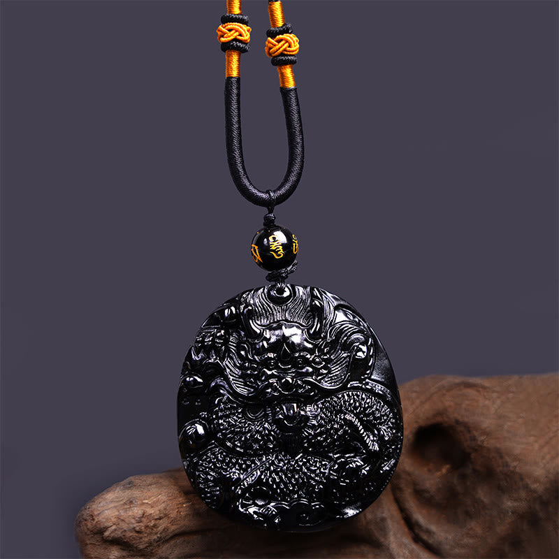 Black Obsidian Round Dragon Pendant – three-quarter dragon disc with gold knot cord on gray, confident