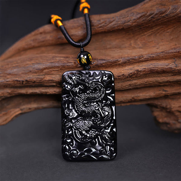 Black Obsidian Dragon Pendant – full dragon body coiled on braided cord with mantra bead on driftwood, auspicious